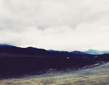 Scenic view of road by mountains against sky