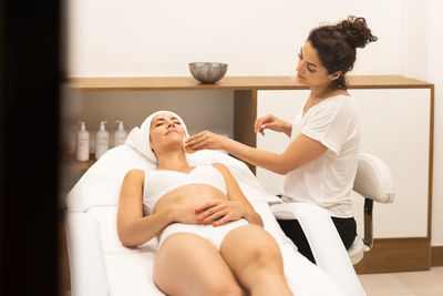 Beautician cleaning face of woman at spa