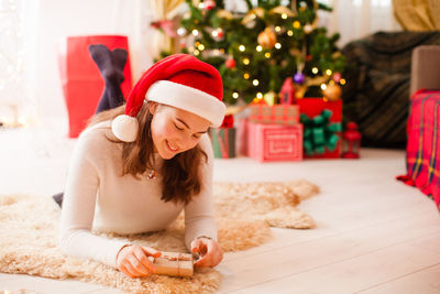 Full length of woman with christmas decorations on floor at home
