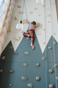 Young boy indoor rock climbing with his father instructor. hobby or home sport 