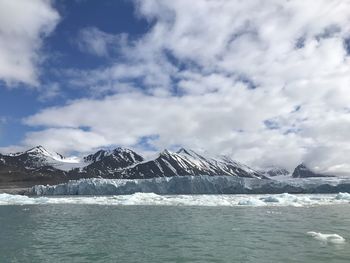 Scenic view of sea and snowcapped mountains against sky