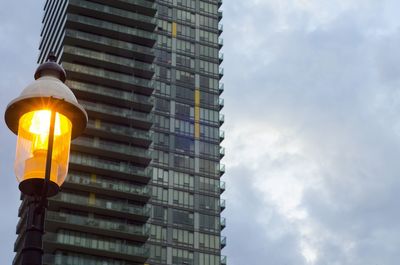 Old fashioned light shining against a modern condo building