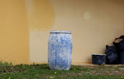 Blue plastic barrel, with drops of paint, on the background of a yellow wall