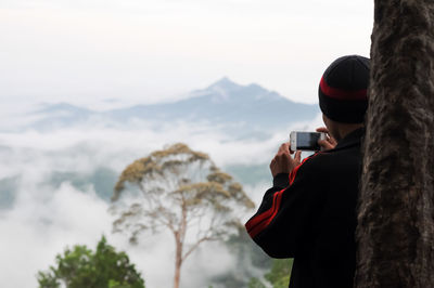 Man photographing on mountain against sky