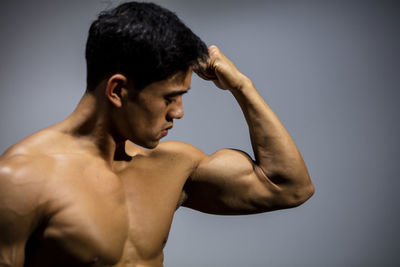 Shirtless muscular man standing against wall