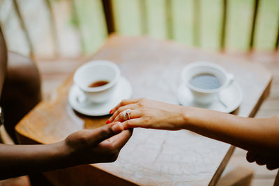 Cropped image of man holding woman hand at cafe