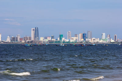 Sea by buildings against sky in city