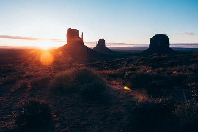 Scenic view of rocks on field against sky during sunset