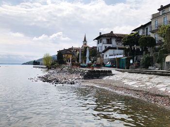 Buildings by river against sky