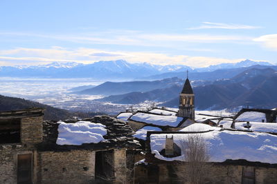 Snow covered buildings and mountains against sky