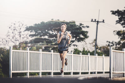 Full length of woman running on footpath against sky