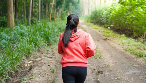 Rear view of woman walking on footpath in forest