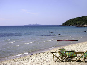 Chairs on beach against sky