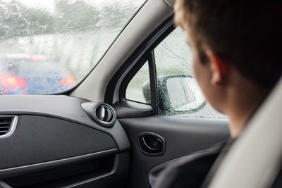 A passenger of a car looks out the window at heavy rain.