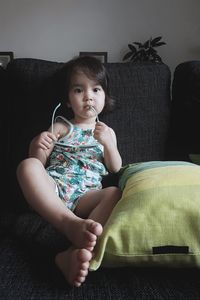 Portrait of girl sitting on sofa at home