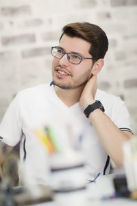 Young man sitting against wall