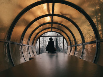 Woman sitting in illuminated tunnel