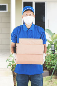 Portrait of delivery person holding parcel standing outdoors