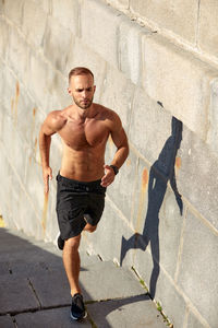 Portrait of shirtless man standing on footpath