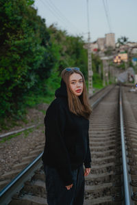Portrait of young woman standing on railroad track