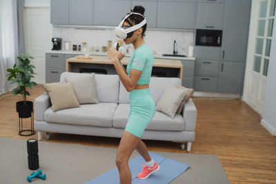 Full length of young woman sitting on sofa at home