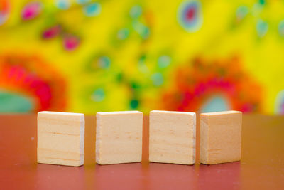 Close-up of wooden blocks on table against multi colored background