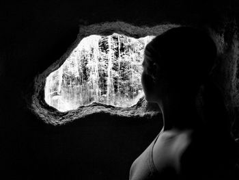 Side view of shirtless young woman in cave