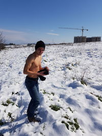 Full length of shirtless man standing on snow