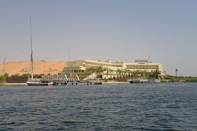 Sailboats on sea by buildings against clear sky