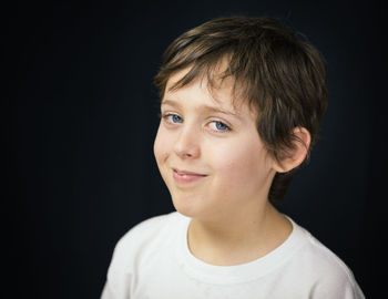 Portrait of smiling boy against black background