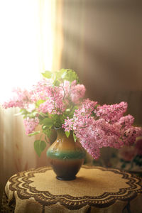 Close-up of pink lilacs flower vase on table. vertical frame.