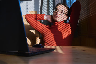 Midsection of woman using mobile phone while sitting on table