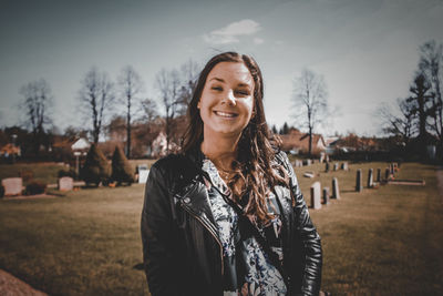 Portrait of young woman standing at cemetery