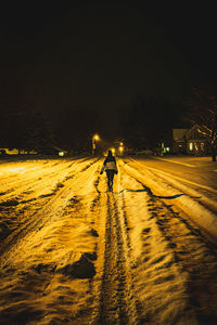 Rear view of man walking on snow covered road