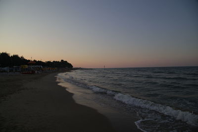 Scenic view of beach against clear sky during sunset