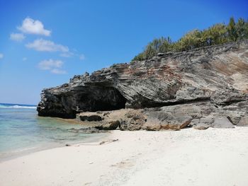 Rock formation on beach against sky