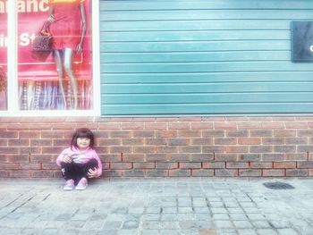 Full length of girl standing against brick wall