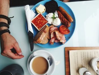 Close-up of man hand by meal in plate on table