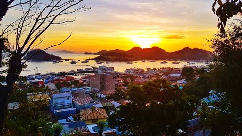 High angle view of townscape by sea against sky at sunset