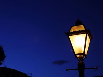 Low angle view of illuminated street light against blue sky