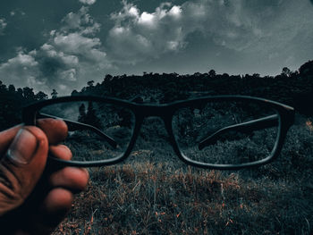Close-up of hand holding eyeglasses on field