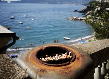 Close-up of cigarette butts in metal container against sea