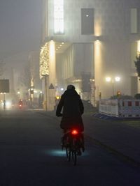 Rear view of man riding motorcycle on road at night