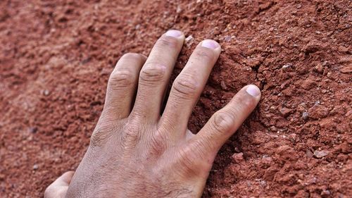 Cropped hand of man touching rock