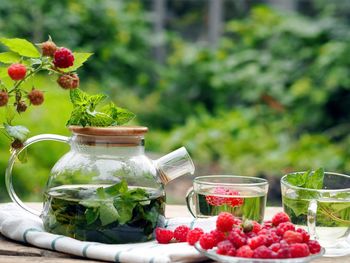 Autumn warming medicinal tea with raspberry and mint in a glass cup and teapot 