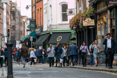 People walking on street amidst buildings in city