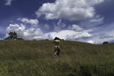 Rear view of man on field against sky