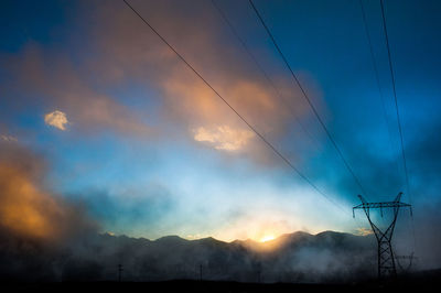 Electricity pylon on landscape against cloudy sky