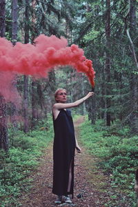 Woman with red smoke flare in forest