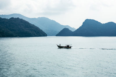 Boat sailing in sea against mountains